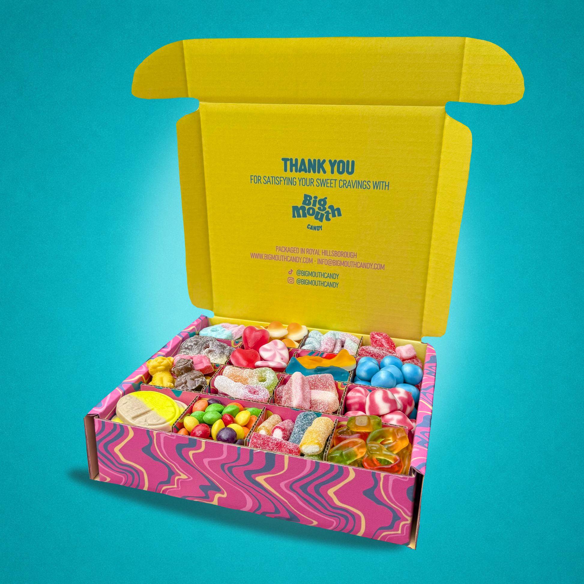 Open box of assorted candies with a colorful interior on a teal background